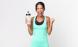 © kues1 - young hispanic woman shouting aggressively with an angry expression and holding a water bottle. fitness concept