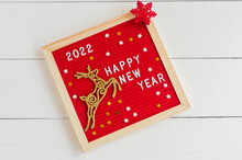 Happy New Year 2022. Letter Board With Golden Deer And Red Flake On A White Background. Flat Lay.