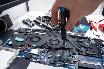 Laptop repair in a workshop, male hand holds a screwdriver