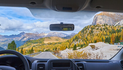 view on the Alps through the windscreen of the car while driving on the curvy road.