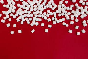 white mini marshmallows on red background, top view