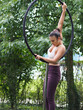 Junge Frau trainiert Pole Dance Sport draußen im Garten