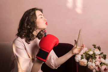 a beautiful girl in a pink dress and boxing gloves paints her lips with lipstick, feminist, copy spa