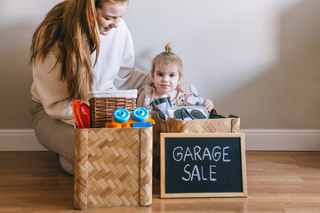 Wall Mural - A young woman and her daughter packed up for a garage sale and donation. Box with the words 