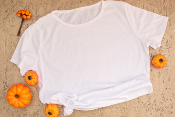 Wall Mural - White t-shirt mockup with halloween decor on gold background. Autumn, halloween and thanksgiving concept