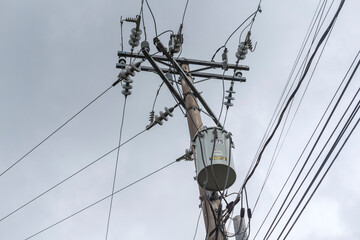 a concrete electric pole with a distribution transformer. during an overcast sky or before a storm.