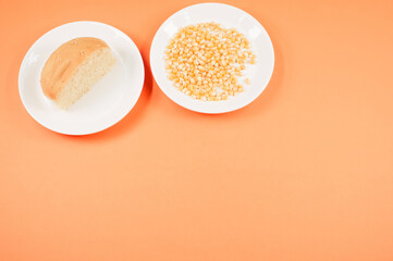 Sticker - Top view of half bread bun and corn grains on a plate isolated on light orange background