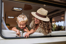 Parent And Child In Camper Van Spend Time Together Playing And Laughing. Carefree Young Mother Travel With Small Kid Boy In Caravan Car. Mom And Little Son Have Fun In Summertime Road Trip Vacation