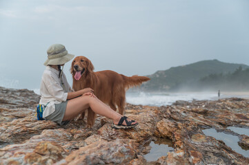 Wall Mural - Golden Retriever and owner on the rock by the sea