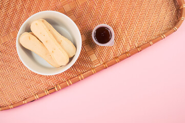 Sticker - Top view of ladyfinger cookies with ketchup dip on a bamboo wicker tray isolated on pink background