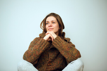 Wall Mural - Smiling woman sitting and holds hands on knees looking away.