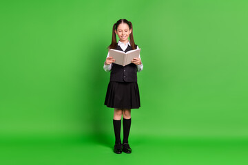 Canvas Print - Photo of funny adorable schoolgirl dressed white black uniform smiling reading book isolated green color background