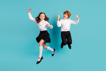 Full length body size view of two cheerful kids jumping having fun isolated over bright blue color background