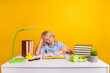 © deagreez - Photo of tired upset schoolboy wear blue shirt sitting desk having read many book isolated yellow color background