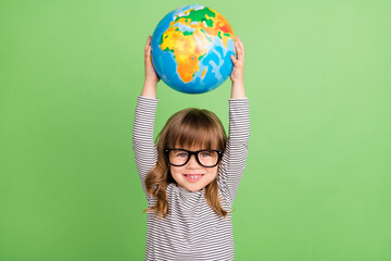 Wall Mural - Photo of cool small blond hair girl hold globe up wear striped shirt isolated on green color backgound