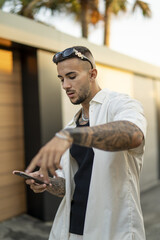 Sticker - Vertical of a Spanish bearded attractive young male looking at the phone  posing in stylish clothes