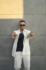 Sticker - Vertical of a Spanish bearded attractive young male leaning on the wall  posing in stylish clothes