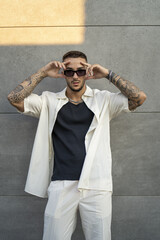 Poster - Vertical of a Spanish bearded attractive young male leaning on the wall  posing in stylish clothes