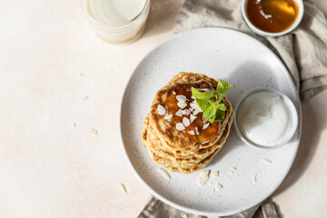 Wall Mural - Healthy oat pancakes with jam, nuts and mint on ceramic plate. Vegan breakfast food. Top view.