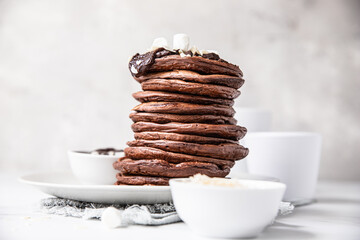 Wall Mural - Chocolate pancakes with melted chocolate, ground almond and marshmallow, light background.