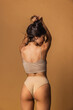 © master1305 - Back view of sportive body of young caucasian woman isolated on brown studio background. Natural beauty concept