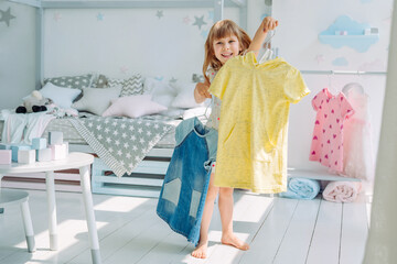 Wall Mural - beautiful little girl choosing a dress in the kids room
