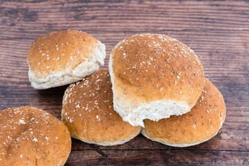 Five freshly baked wheaten rolls on an old oak table