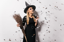 Blithesome Young Witch Drinking Wine. Carefree Woman In Halloween Attire Posing At Party.