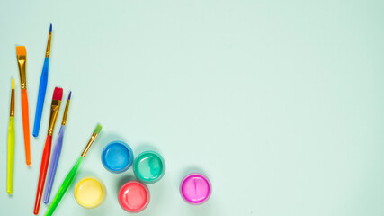 Multicolored paint brushes and paint cans on a blue background