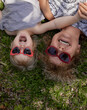 © Hanna - Happy little girl in red glasses is playing with her grandmother lying on the grass in the garden