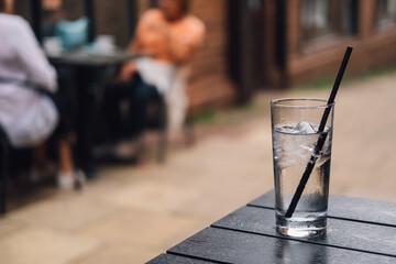 Poster - Shot of a glass of pure, refreshing water with ice on the table with a blurred background of cafe