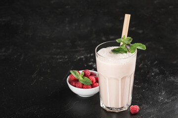 Lassi drink with raspberries in a glass with mint and a bamboo tube on a dark background.