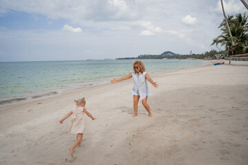 Wall Mural - Happy girl playing with her grandmother on the beach