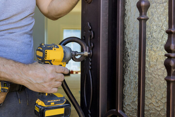 Wall Mural - Locksmith hand holds the screwdriver in installing new house door lock