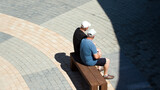 Fototapeta  - Dwoje mężczyzn w białych czapkach siedzących na drewnianej ławce