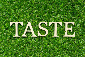 Poster - Wood letter in word taste on green grass background