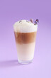 Glass of tasty lavender latte with flowers on color background