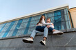 © somemeans - Date of a young couple. Girl is sitting on the lap of the guy. Modern city building on the background. Bottom view