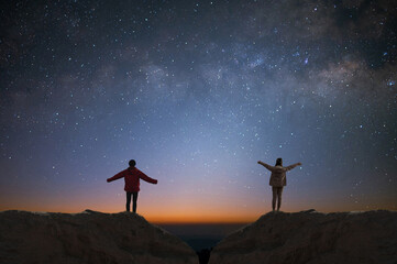 Wall Mural - Silhouette of travelers couple and backpacker watched the star and milky way alone on top of the mountain. They enjoyed traveling and was successful when he reached the summit.