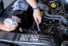 Auto mechanic working repairing a car engine with an open-end spanner in a garage