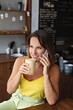 © ksenija1803z - portrait of smiling woman with cup of coffee in her hand and talking o smartphone