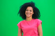 © kinomaster - Portrait of young female African American smiling happily. Black woman with curly hair in pink tshirt poses on green screen in the studio. Close up.