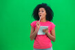 © kinomaster - Portrait of young female African American thinking, then happy writing with pen in notebook. Black woman with curly hair poses on green screen in the studio. Close up.