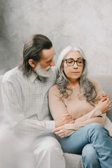 Wall Mural - Senior couple in casual clothes sitting on couch in living room