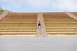 © Cavan Images - Rear view of a young student with backpack going up stairs of bleacher