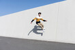 © Cavan Images - Young man jumping on the urban wall background