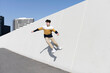 © Cavan Images - Young man jumping on the urban wall background