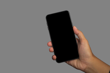 Wall Mural - hand holding of a smartphone with a gray background. close-up photo. space for text. technology and 