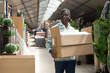 © JackF - Positive African American man holding boxes with goods bought in home decor department of hypermarket