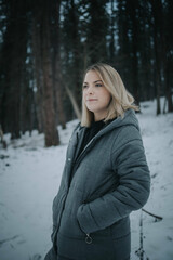 Poster - Vertical shot of a young European blonde lady wearing winter clothes in a snowy park